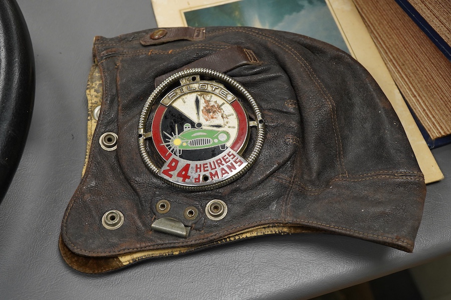 Racing ephemera, including; a Moto-lite steering wheel, a driver's leather cap, an enamelled Le Mans pilot’s radiator badge, signed photograph of Prince Michael Kent standing next to a 12 cylinder single seat racing car